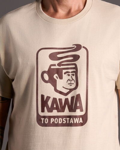 Jasnobeżowa koszulka w kolorze piaskowego beżu marki Dziedzic Pruski z charakterystyczną grafiką przedstawiającą wizerunek głowy Dziedzica Pruskiego zamieniony z filiżankę pełną gorącej aromatycznej, świeżo zaparzonej kawy z ziaren arabica. Autorska grafika przedstawia ciekawie zakomponowany napis wykonany specjalną czcionką o treści KAWA TO PODSTAWA.